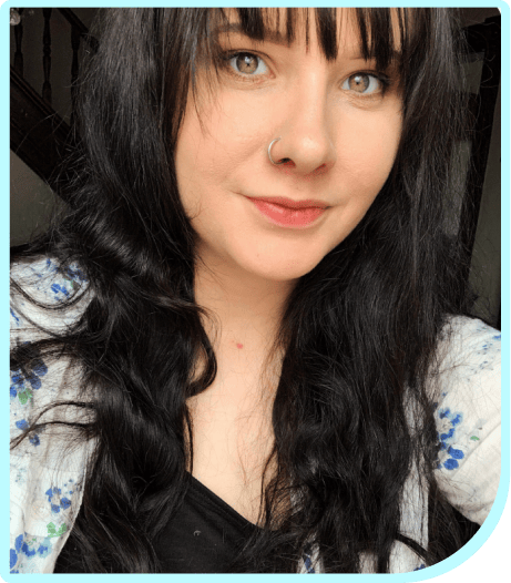 A woman with black hair and green eyes is posing for a photo.